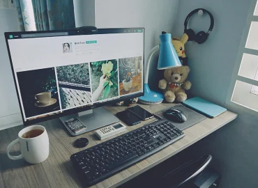 B2D - Weboldal struktúra, egy munkaasztal, monitorral ami egy weboldalt mutat, billentyűzettel, egérrel és egy bögre kávéval